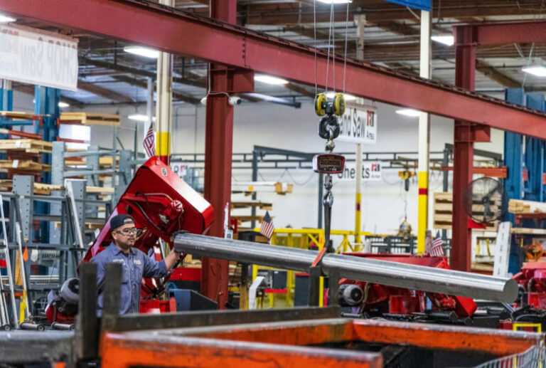 A man operates a machine in a factory, focused on his task amidst industrial equipment and surroundings. 2025