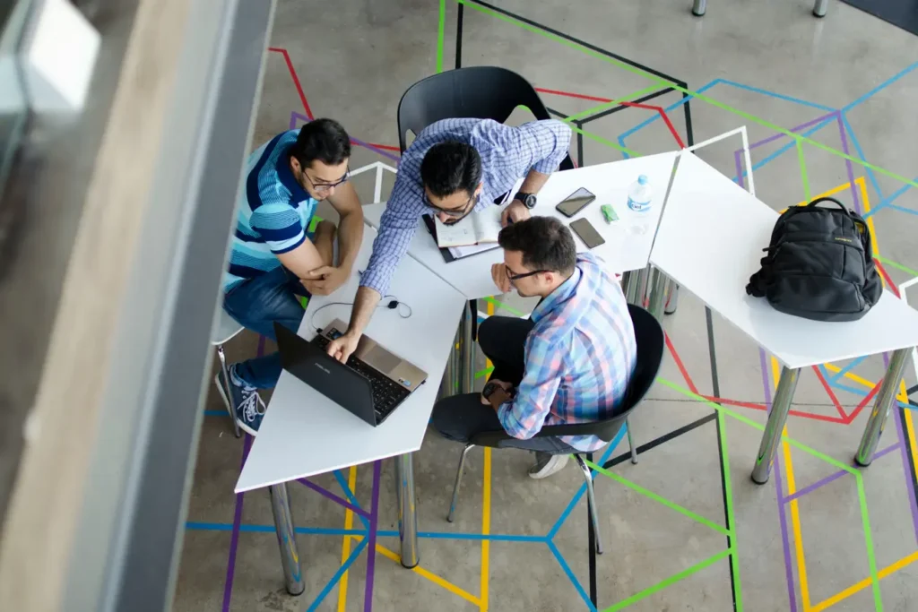 A group of three people at a table, focused on their laptops, working together on a project.