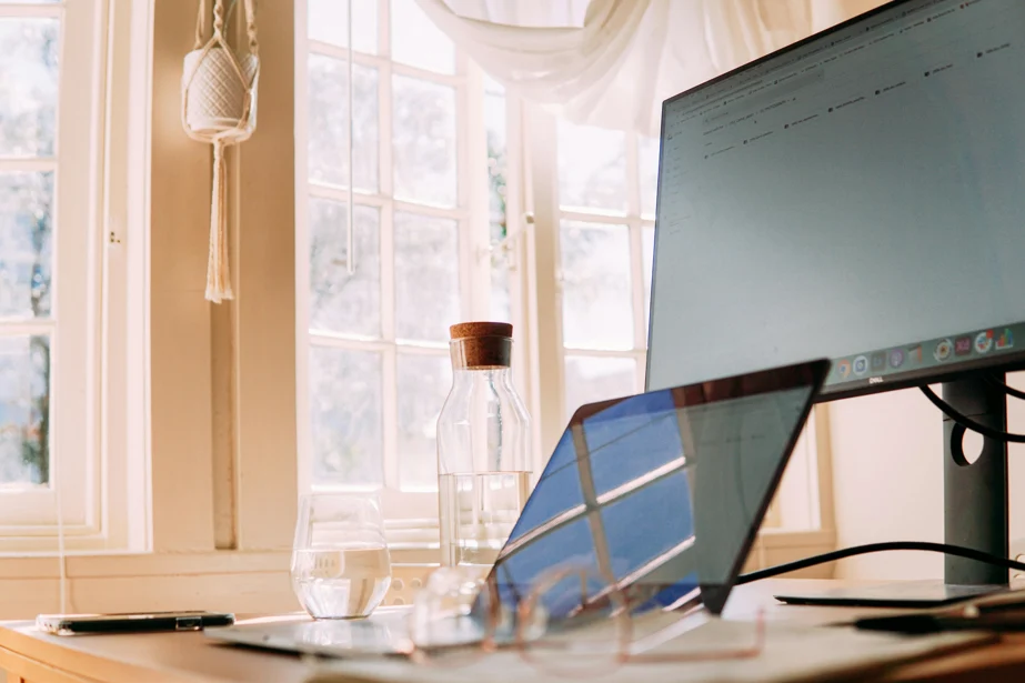 A computer monitor on a desk beside a laptop, showcasing a workspace setup for productivity and multitasking.