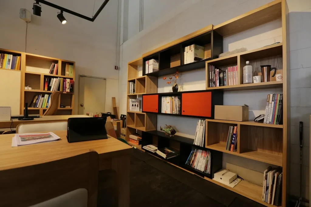 An office space with a desk, several bookshelves, and a laptop positioned on the desk.